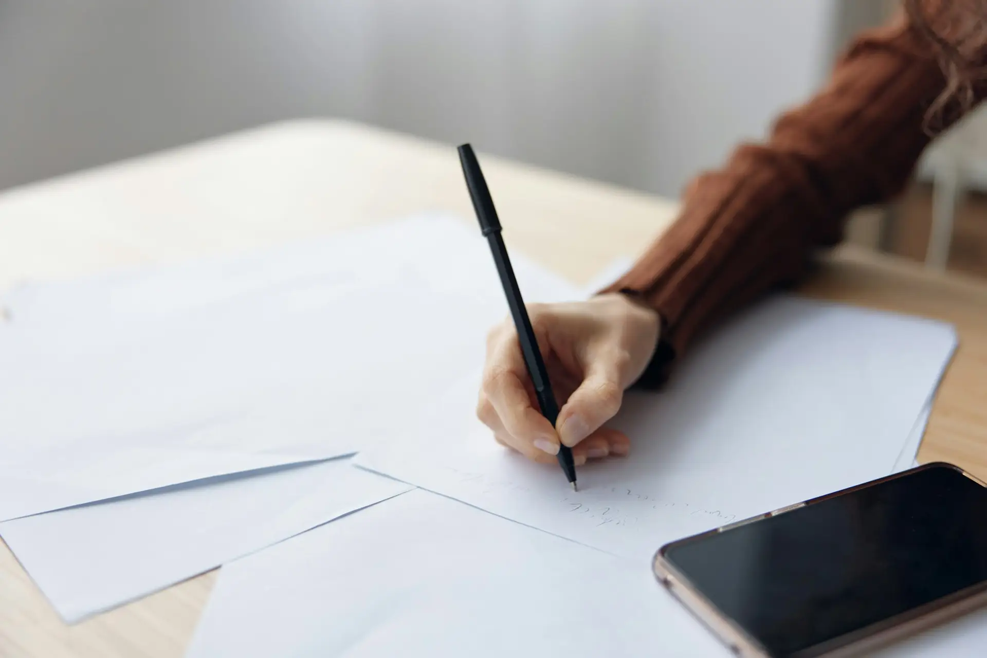 Closeup shot of woman's hand writing script counts taxes calculates budget for purchases on papers