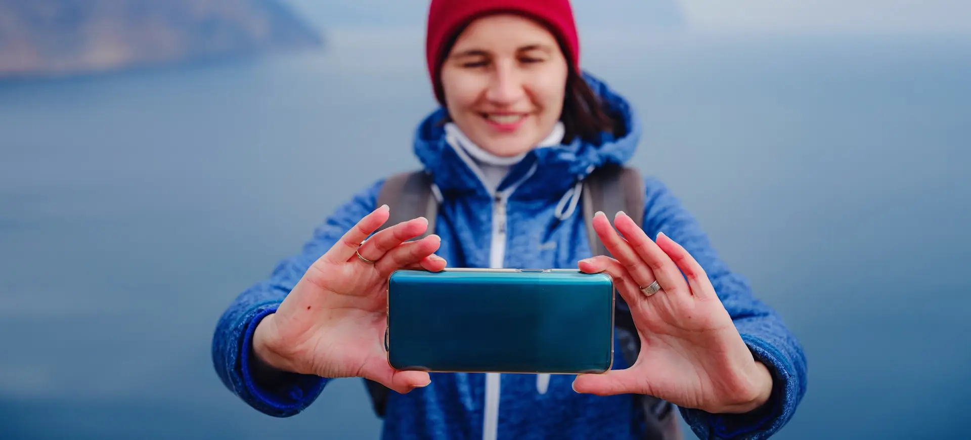 woman take photo of sea on smartphone