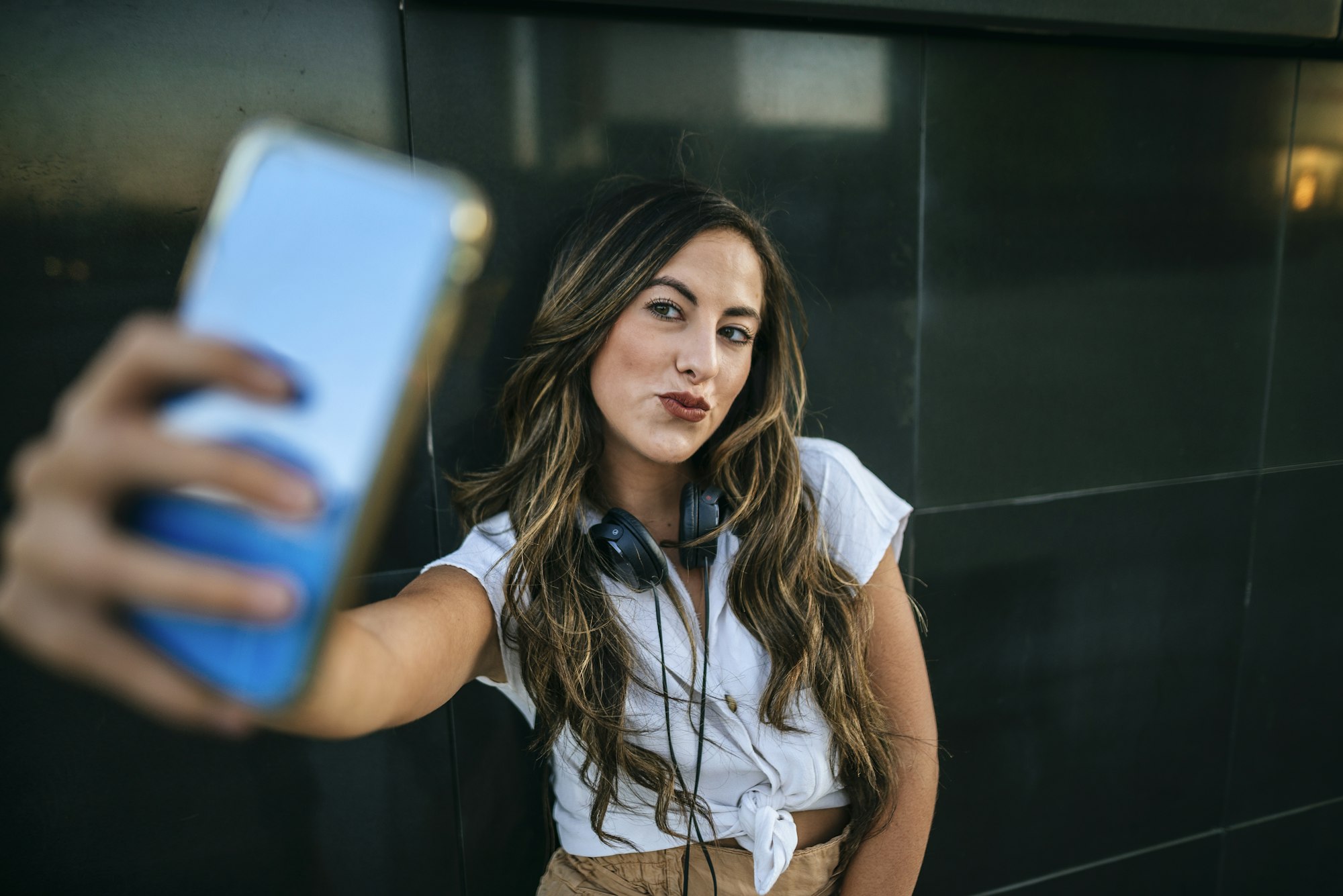 Young woman taking a selfie with her smartphone, pouting mouth