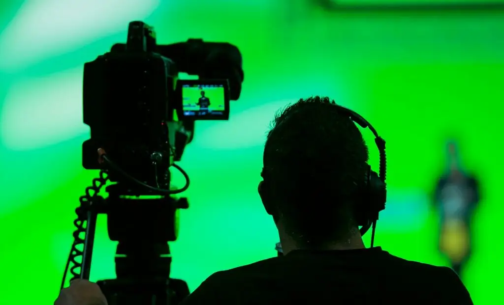 Back view of a videographer next to a recording camera