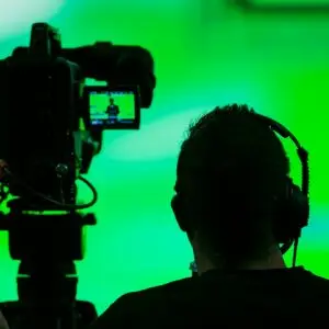 Back view of a videographer next to a recording camera