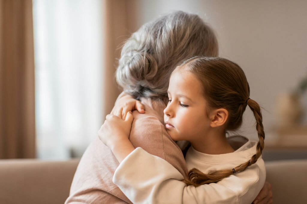 Little Girl Hugging Older Woman on Couch