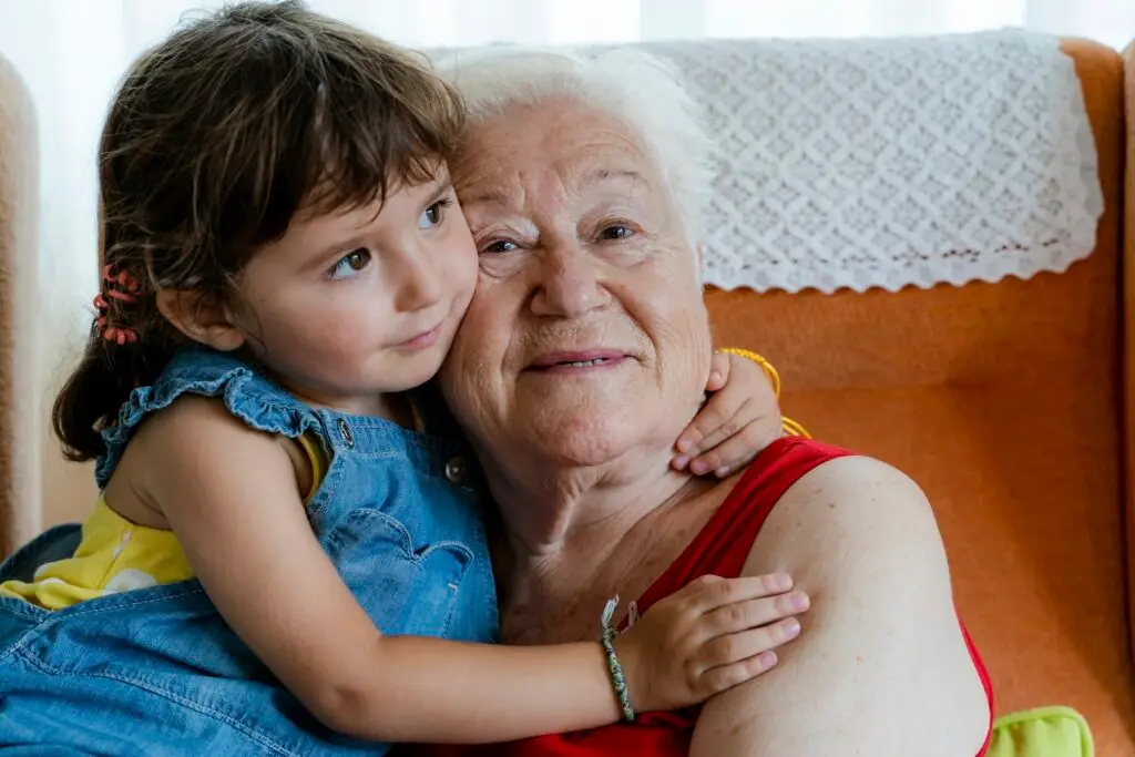 Smiling grandmother hugging her granddaughter at home